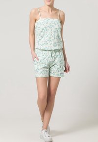 Ensemble à deux pièces à imprimé floral comprenant un haut sans manches et un short à cordon. Principalement vert clair avec de petites fleurs violettes et bleues.