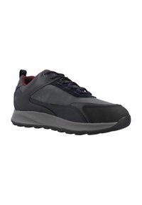Zapato deportivo negro con parte superior de cuero liso, cuello acolchado y suela de goma flexible. Presenta cordones oscuros y un acento burdeos.