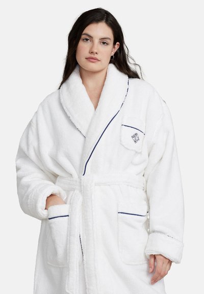 White plush bathrobe with a shawl collar, navy blue piping, and two front pockets. Features a small logo on the chest pocket.