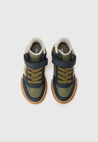 Grønne og marineblå sneakers med teksturert stoff, polstret krage, gule lisser og borrelåsspenne, med gummisåle og logo innersåle.