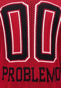 Κόκκινο πλεκτό ύφασμα με μεγάλο μαύρο και άσπρο περίγραμμα «00» και μαύρο κείμενο «PROBLEMO» από κάτω.