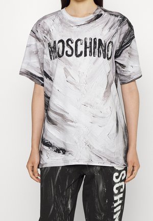 Weißes und schwarzes T-Shirt mit abstraktem Druck, "MOSCHINO" in fettgedruckten schwarzen Buchstaben, kurzen Ärmeln und lockerem Schnitt. Weiche Stofftextur.