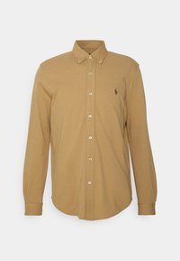 Camisa de manga larga con botones en algodón color beige, presenta un cuello estándar, cierre frontal con botones y un pequeño logo bordado en el pecho.