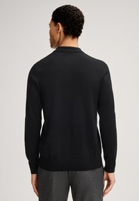 Schwarzer Strickpullover mit Kragen und langen Ärmeln. Verfügt über gerippte Bündchen und Saum, glatte Textur und eine taillierte Passform.