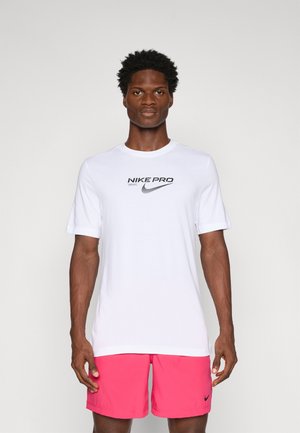 White Nike Pro T-shirt with short sleeves and black logo on the chest, paired with pink athletic shorts featuring a small black logo.