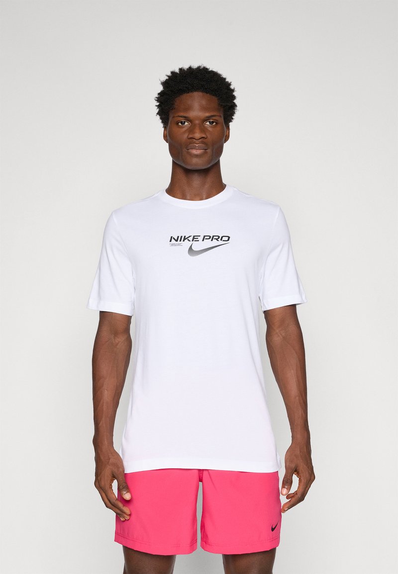 White Nike Pro T-shirt with short sleeves and black logo on the chest, paired with pink athletic shorts featuring a small black logo.