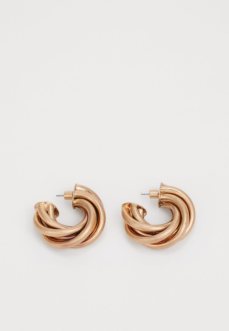 Metalliske gulløreringer i en vridd design. Rund form med en glat, skinnende overflate og pinlås. Betydelig bredde og dybde.