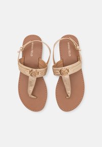 Sandales beiges avec une semelle plate, des bretelles dorées texturées avec une boucle décorative, et un design simple de tongs.