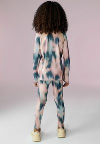 Růžovo-modrý tie-dye atletický set vyrobený z elastického materiálu, dlouhý rukáv top, odpovídající legíny a tenisky s robustní podrážkou.