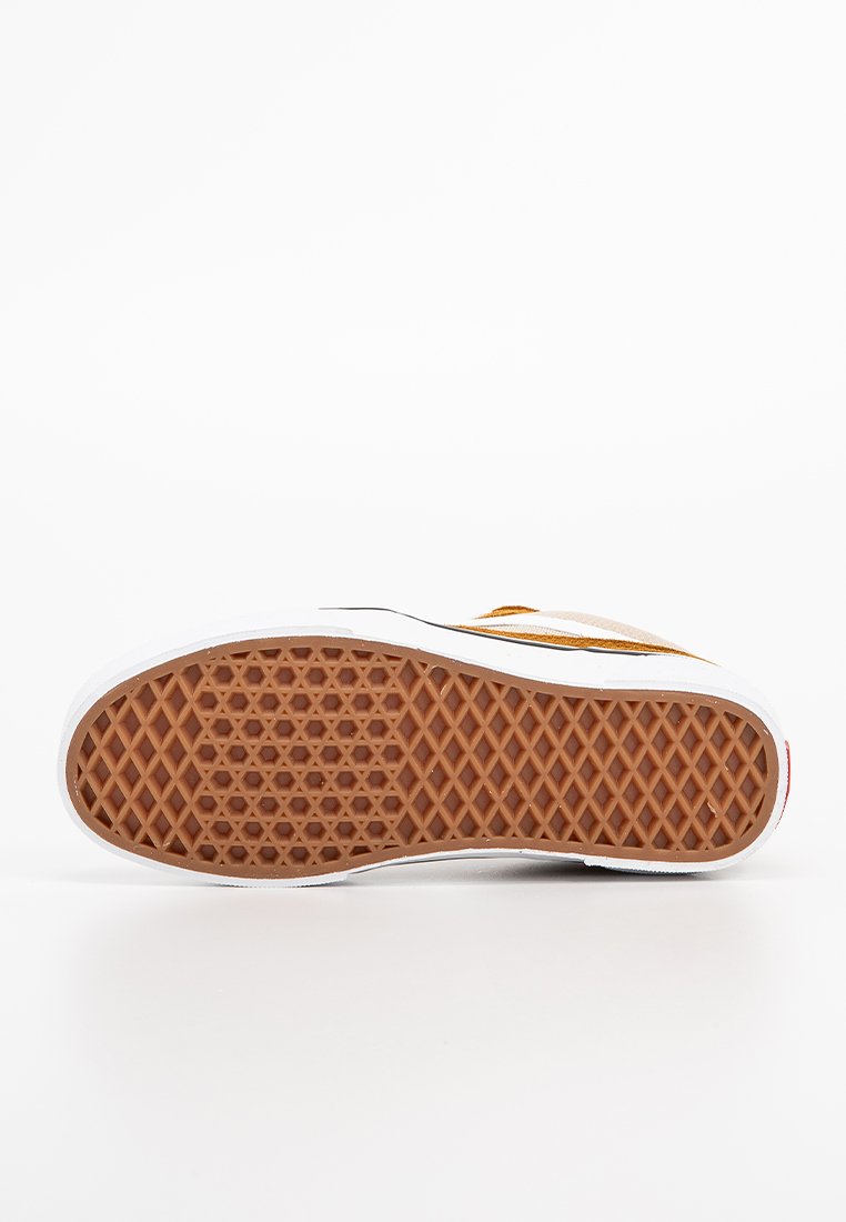 Suela de una zapatilla con agarre de patrón de waffle marrón, mediasuela blanca y parte visible de la parte superior marrón y blanca sobre un fondo blanco.