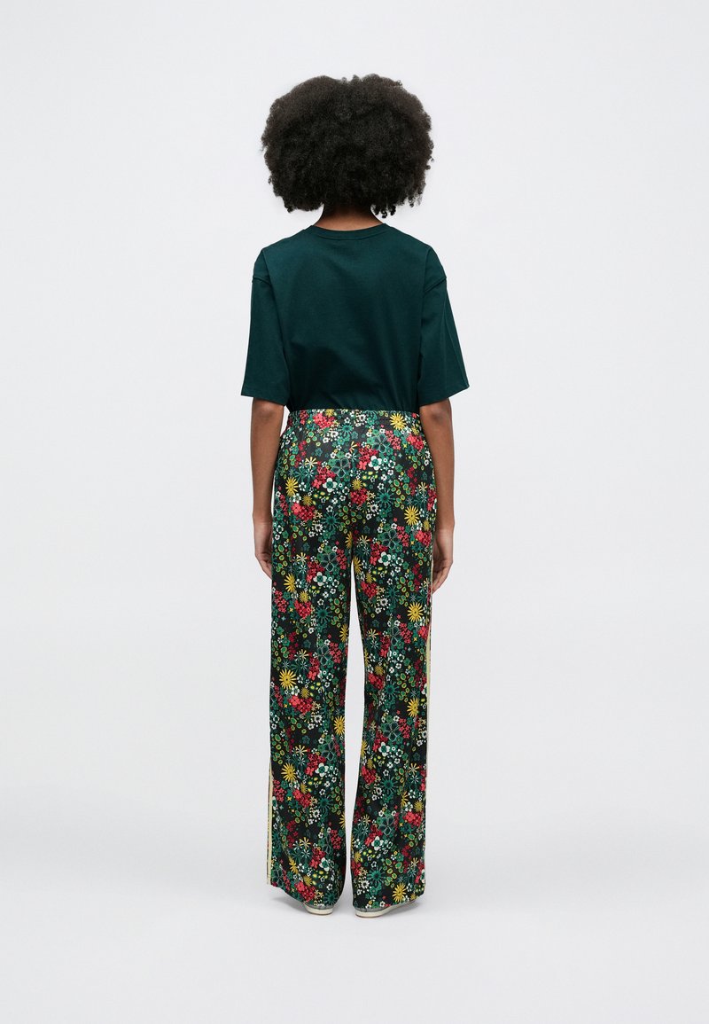 Green short-sleeve shirt paired with wide-leg floral print trousers featuring multicolored flowers on a dark background.