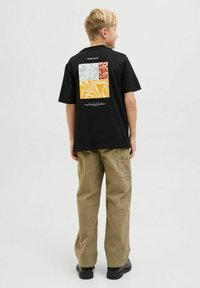 Tricou din bumbac negru, cu un model pătrat colorat, cu accente roșii, galbene și albastre pe spate, asortat cu pantaloni cargo khaki.