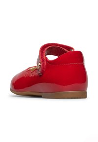 Roter Lacklederschuh mit abgerundetem Zehenbereich, flacher Sohle und verstellbarem Samtband mit goldener Knopf-Akzentuierung. Glatte und glänzende Textur.