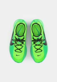 Baskets de sport vertes avec une tige texturée, des accents noirs et des lacets. Présente un logo Nike bien visible et un design épuré.