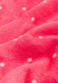 Mehka, rožnata flis tkanina z gladko teksturo, ki ima po površini enakomerno razpršene majhne bele pikice.