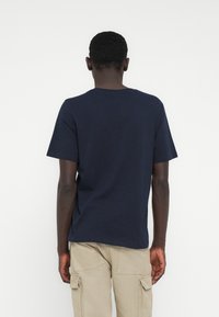 Camiseta de algodón azul marino con mangas cortas y cuello redondo, con un diseño sencillo y un ajuste relajado, vista desde atrás.