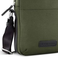 Borsa a tracolla in tessuto verde con superficie testurizzata, accenti in pelle nera, tracolla regolabile e un design elegante. Presenta una toppa con il logo.