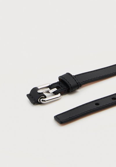 Μαύρη δερμάτινη ζώνη με ασημένια μεταλλική αγκράφα και πολλαπλές τρύπες, τοποθετημένη επίπεδα σε ανοιχτό φόντο.