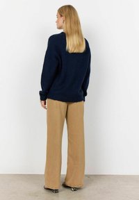 Pulover tricotat bleu marin cu un croi lejer și mâneci lungi, asortat cu pantaloni cu talie înaltă din bej, cu un textil moale și marginile desfăcute.