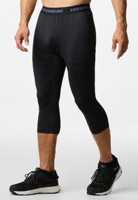 Black fitted capri pants made of stretchy fabric, featuring a waistband with "SWEDEMOUNT" logo and a smooth texture throughout.