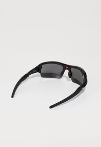 Gafas de sol deportivas negras con lentes oscuros, montura curvada, almohadillas de goma en la nariz y brazos elegantes y afinados para un ajuste seguro.