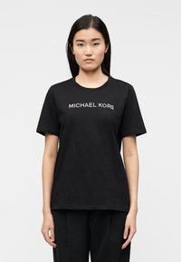T-shirt preta de algodão com mangas curtas e decote redondo, com o logótipo "MICHAEL KORS" em texto branco contrastante na frente.