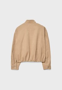 Veste beige en velours côtelé avec manches longues, poignets à boutons-pression et taille élastiquée froncée, vue de dos sur fond uni.