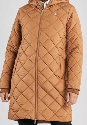 Veste longue matelassée marron avec fermeture éclair à l'avant, poches latérales, capuche et poignets côtelés, portée par-dessus une chemise blanche.