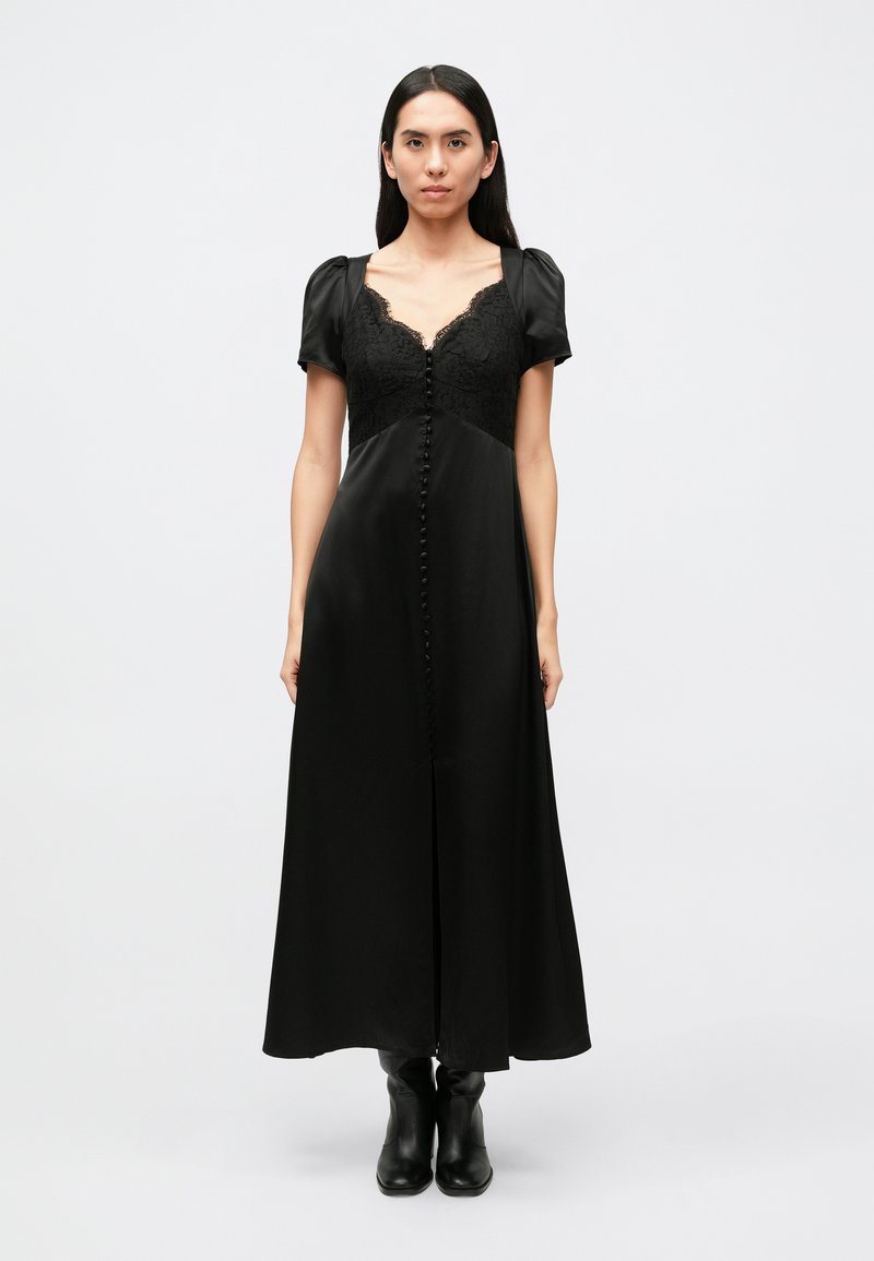 Lange zwarte jurk met een kanten lijfje, korte pofmouwtjes en een rij knopen aan de voorkant. Glad stof met een vloeiende silhouet.