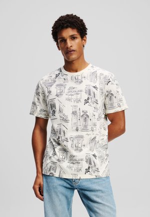 Short-sleeve t-shirt in cream, featuring black line art of Parisian cafes and buildings, with a crew neckline and relaxed fit.
