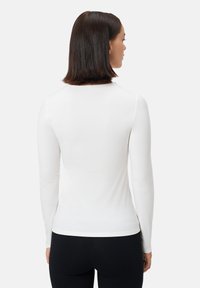 Bílý dlouhý rukáv top vyrobený z hladké látky, s kulatým výstřihem a přiléhavým střihem, s jednoduchým zadním dílem a bez viditelných vzorů.