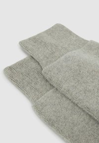 Graue Socken aus weichem, strukturiertem Material mit gerippten Bündchen. Der Stoff hat eine glatte Oberflächenbeschaffenheit und subtile Farbvariationen.