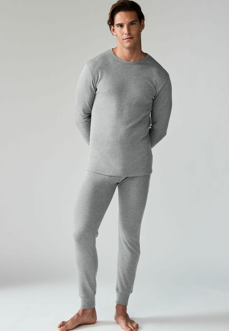 Graues langärmeliges Thermoshirt und passende enganliegende Hosen aus strukturiertem Stoff, mit gerippten Bündchen an den Knöcheln und Handgelenken.