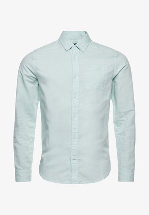 Lichtblauwe langwerpige overhemd met knopen en kraag, met een borstzak, weergegeven op een witte achtergrond.