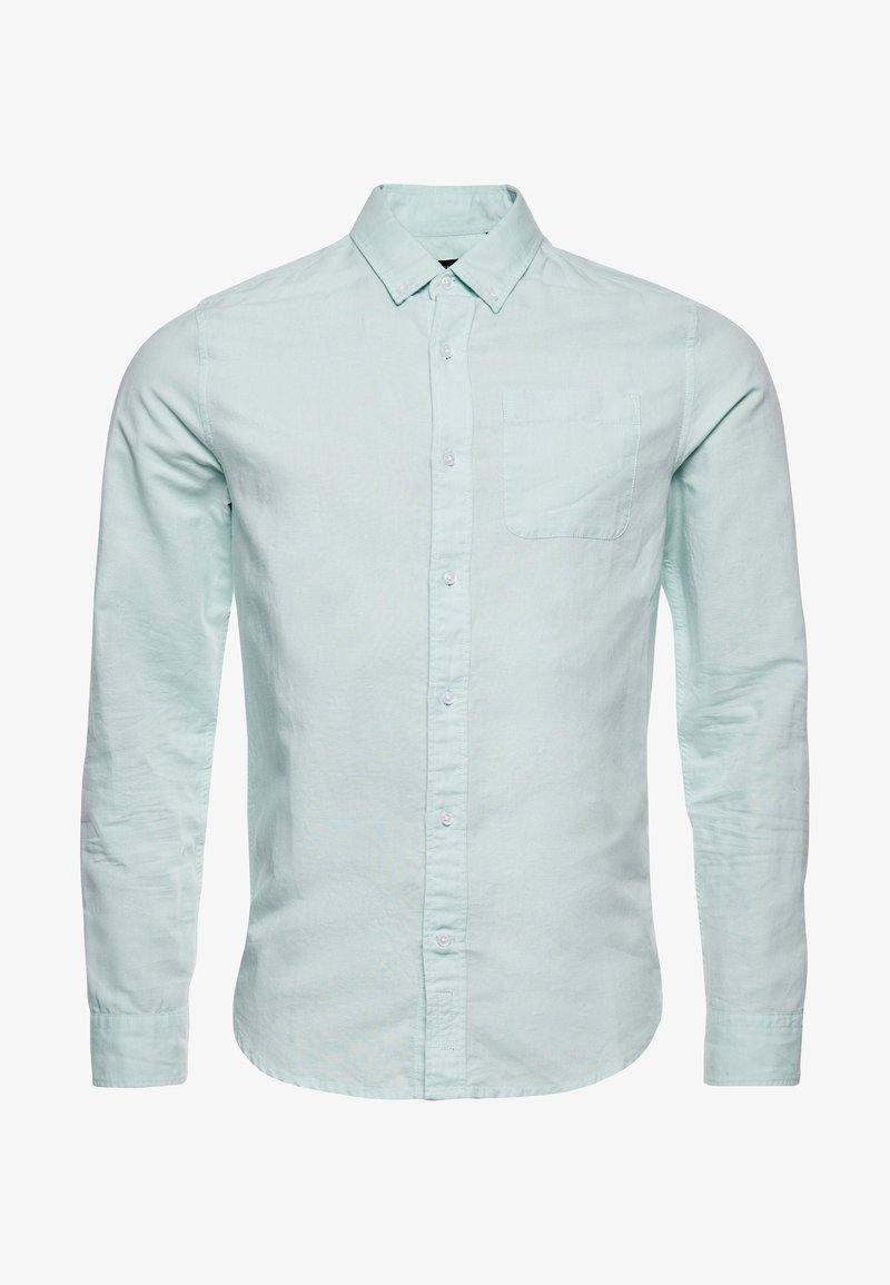 Lichtblauwe langwerpige overhemd met knopen en kraag, met een borstzak, weergegeven op een witte achtergrond.