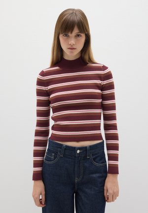 Maglietta a maniche lunghe borgogna a coste con strisce orizzontali rosa e crema; scollatura alta; abbinata a jeans in denim blu scuro.