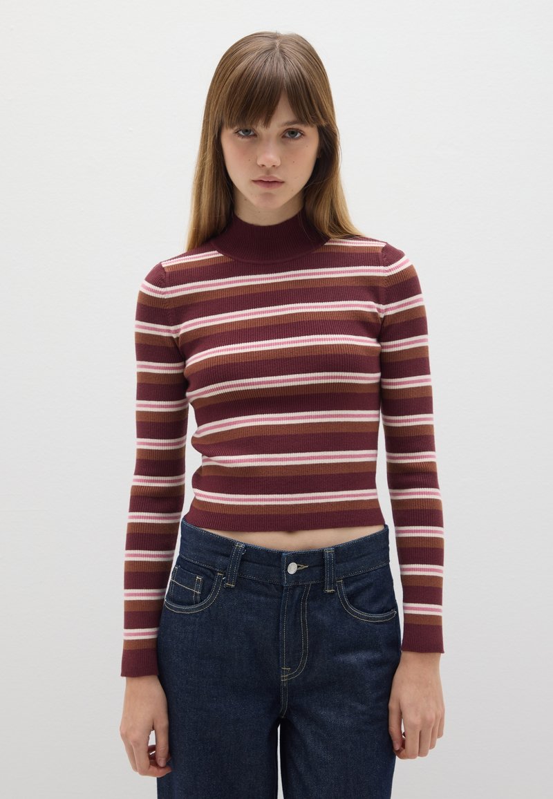 Camiseta de manga larga de canalé color burdeos con rayas horizontales en rosa y crema; cuello alto; combinada con jeans de mezclilla azul oscuro.