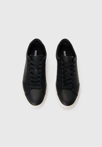 Zwarte sneakers met een gladde matte neus en gestructureerde zijkanten. Voorzien van zwarte veters, rubberen zool en logo op de binnenzool.