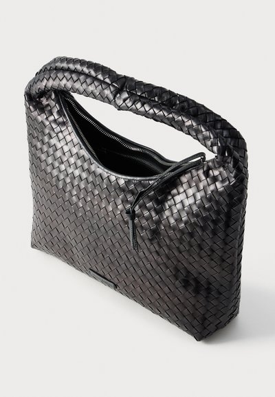 Πλεκτή μαύρη δερμάτινη τσάντα χειρός με φερμουάρ, με ευρύ λουρί και υφή στην επιφάνεια. Συμπαγής ορθογώνιο σχήμα με λείο εσωτερικό.