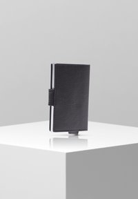 Portafoglio in pelle nera con superficie strutturata, design piegato e chiusura laterale. Presenta un profilo sottile e uno slot per carte trasparente.