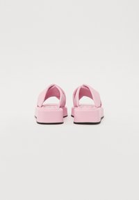 Rosa plattform sandaler med polstrede kryssremmer og en tykk såle. Designet har en glatt tekstur og en litt avrundet form.