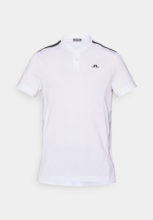Polo shirt blanc à manches courtes, avec col à boutons et accents noirs sur les épaules. Tissu respirant avec une texture lisse.