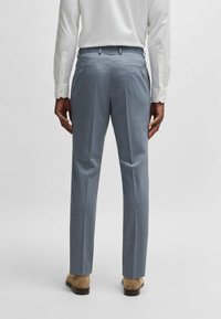 Light blue tailored trousers with a textured finish and sharp creases, featuring two back pockets and a sleek fit.