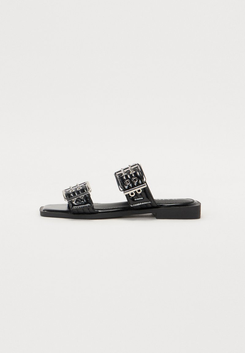 Musthave musta lamed, millel on kaks dekoratiivset konksu hõbedase riistvara ja sujuv nahk. Minimalistlik disain ja nelinurkne kuju.