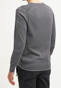 Grå tröja i mjukt material, med rund halsringning, ribbade ärmslut och nederkant, sidofickor och en avslappnad passform.