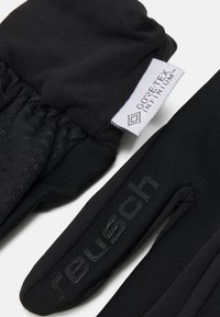 Schwarze Handschuhe aus weichem, elastischem Stoff mit einem strukturierten Bündchen. Enthält ein weißes Gore-Tex-Etikett und eine erhabene Reusch-Markierung auf der Handfläche.