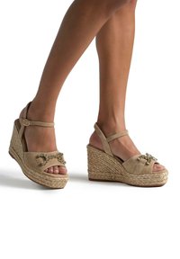 Sandali con zeppa beige con suola in juta in stile espadrilla, morbidi cinturini in camoscio e dettagli gioiello sulla parte anteriore. Design open-toe.