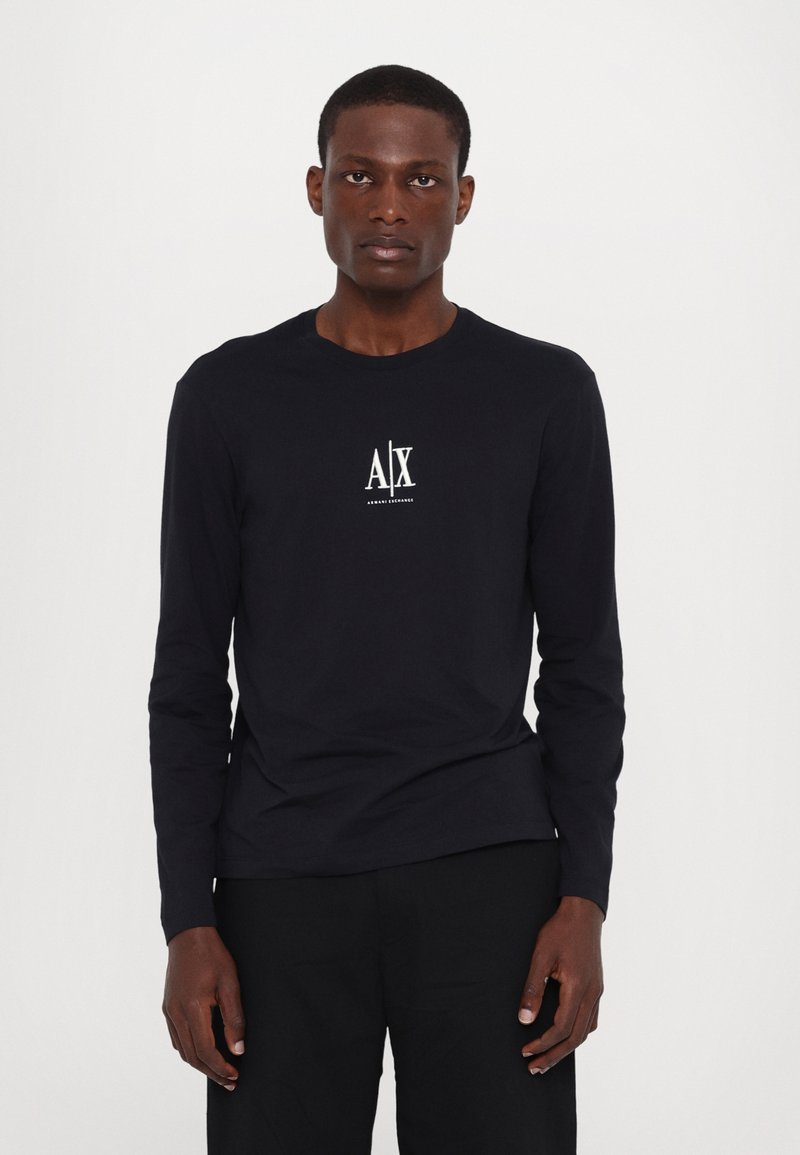 Katoenen T-shirt met lange mouwen in marineblauw, met een wit logo op de borst, ronde hals en een getailleerd design. Effen kleur zonder patronen.