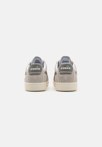 Sneakers in pelle grigia e bianca con finitura in suede texturizzato, dotati di una suola in gomma e dettagli con logo sul tallone.