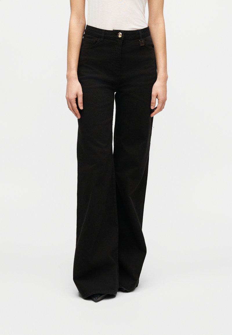 Μαύροι παντελόνες με φαρδιά μπατζάκια από ανθεκτικό τζιν ύφασμα, με κούμπωμα με κουμπιά στο εμπρός μέρος και πλαϊνές τσέπες, με ομαλή υφή και χωρίς ορατά σχέδια.